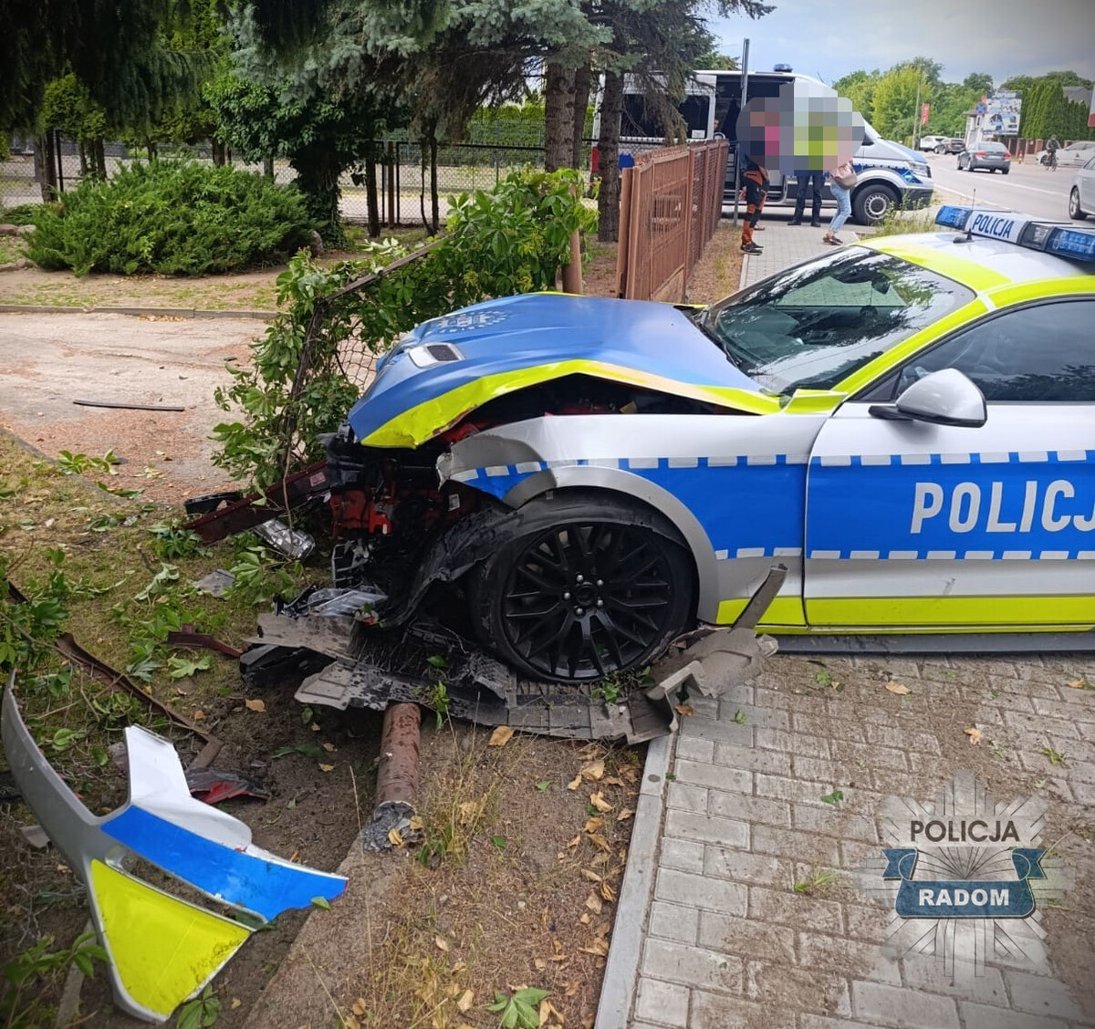 Uszkodzony policyjny Mustang po uderzeniu w ogrodzenie posesji