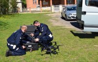 Dwaj umundurowani policjanci przygotowują drona do startu