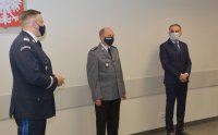 Osoby, w tym policjanci, stojące przy ścianie