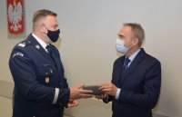 Policjant i osoba cywilna stojące przy ścianie