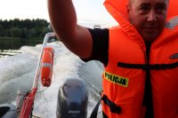 Policjant w pomarańczowej kamizelce na policyjnej łodzi