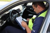 Policjant siedzący w radiowozie wypełnia dokumentację