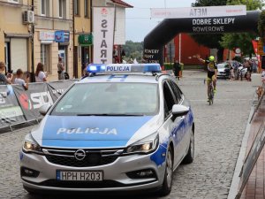 radiowóz policyjny oraz zwycięzca wyścigu kolarskiego