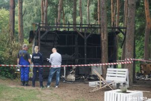 Osoby stojące przed podpalonym budynkiem