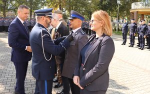 Plac, na którym stoją policjanci w mundurach oraz osoby cywilne