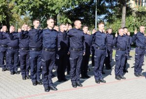 Plac, na którym stoją policjanci w mundurach oraz osoby cywilne