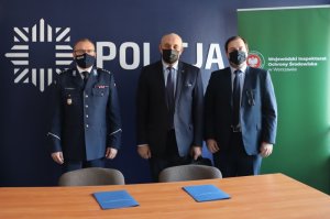 Uczestnicy spotkania i podpisania porozumienia stojący za stołem w sali