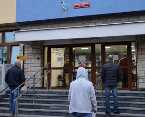 mężczyźni stojący przed budynkiem Komendy Wojewódzkiej Policji zs. w Radomiu