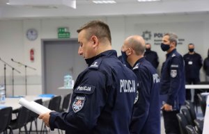 policjanci stojący na sali w budynku Komendy Wojewódzkiej Policji zs. w Radomiu