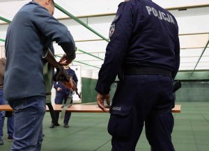 mężczyzna który stoi obok policjanta i rozkłada broń