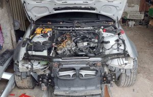 Częściowo zdekompletowany przód srebrnego samochodu marki BMW