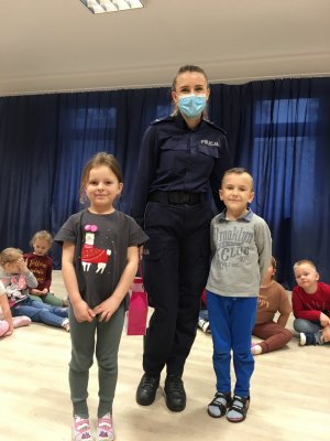 Umundurowana policjantka w maseczce stojąca obok dzieci