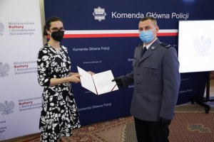 Kobieta wręczająca wyróżnienie umundurowanemu policjantowi