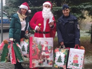 Kobieta, Św. Mikołaj i policjantka trzymają prezenty