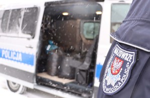 Umundurowany policjant stojący przy radiowozie