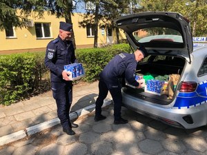 dwóch policjantów podczas wkładania rzeczy do bagażnika radiowozu
