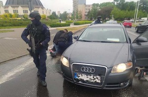 Umundurowani policjanci z bronią obok samochodu