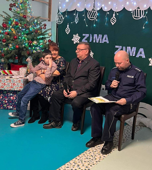 Policjant wraz z innymi osobami siedzący na krześle