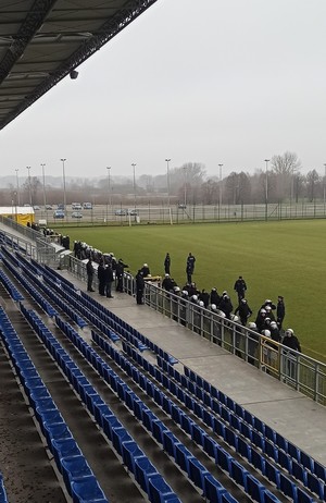 Umundurowani policjanci na płycie stadionu piłkarskiego przed trybunami