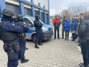 Osoby stojące przed budynkiem komendy
