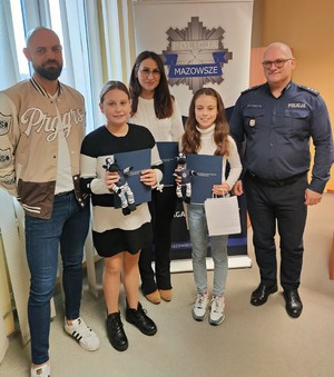 Nagrodzone dziewczynki wraz z rodzicami. Obok stoi policjant