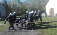 Umundurowani policjanci niosący kolegę