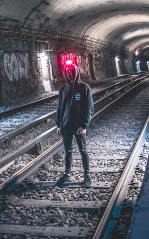 Zamaskowany mężczyzna stojący w tunelu kolejowym