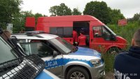 Radiowóz oraz straż pożarna stojące na tle lasu