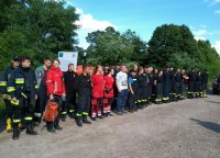Policjanci oraz strażacy stojący na tle lasu