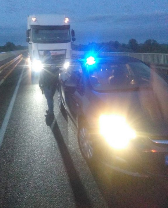 Samochód ciężarowy oraz radiowóz stojące na ulicy