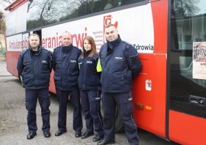 Umundurowani policjanci stojący przed busem do oddawania krwi