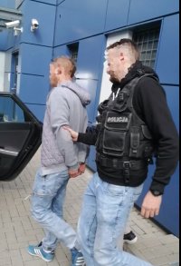 Umundurowany policjant prowadzi zatrzymanego