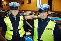 Umundurowani policjanci stojący obok radiowozu