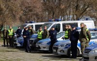 Policjanci i żołnierze stojący przed radiowozami