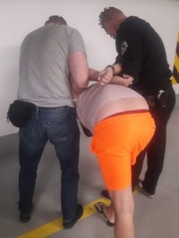Policjanci prowadzą osobę zatrzymaną