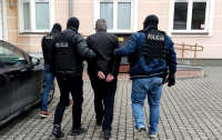 Policjanci operacyjni prowadzą zatrzymanego mężczyznę