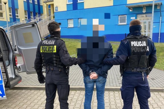 Zatrzymany mężczyzna prowadzony przez umundurowanych policjantów