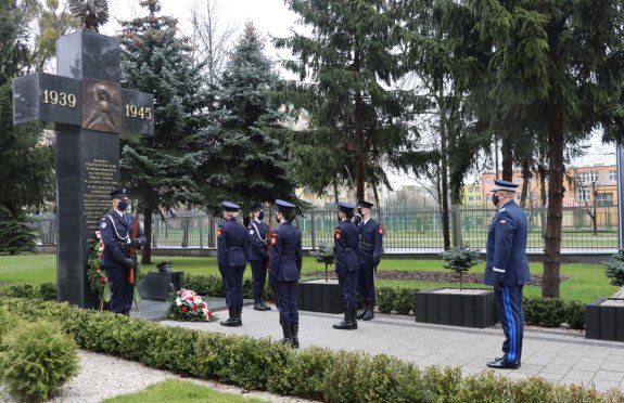 Umundurowane osoby składające kwiaty przed pomnikiem
