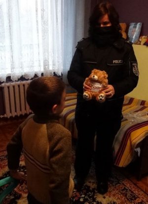 policjantka stojąca z misiem a na przeciw niej chłopiec
