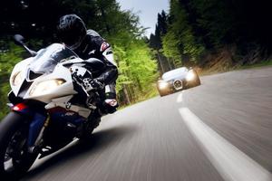 zdjęcie ilustracyjne przedstawiające motocyklistę a za nim sportowy samochód