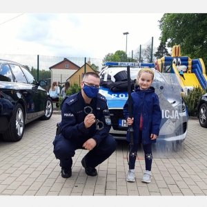 Dziewczynka z policjantem przy radiowozie oznakowanym