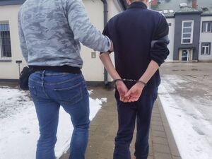 policjant nieumundurowany prowadzi podejrzewanego o popełnienie przestępstwa mężczyznę