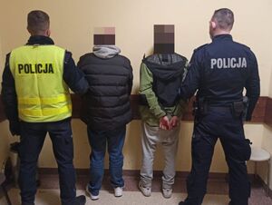 Policjanci stoją tyłem z zatrzymanymi mężczyznami