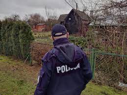 Policjant umundurowany  patroluje teren ogródków działkowych