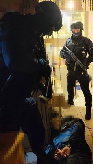 Policjanci umundurowani z grupy realizacyjnej podczas akcji zatrzymania mężczyzny