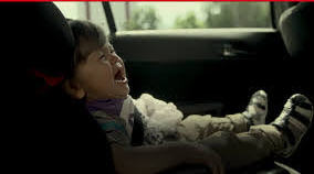 Płaczące dziecko siedzi w foteliku samochodym