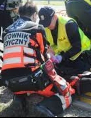Ratownik medyczny i policjant udzielają pomocy osobie poszkodowanej