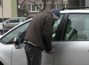 Mężczyzna stoi przed drzwiami od kierowcy pojazdu i próbuje go otworzyć
