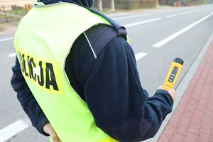 umundurowany policjant trzyma w ręku alkomat