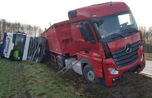 Dwie ciężarówki marki mercedes znajdujące się w rowie, jedna z nich leży na boku